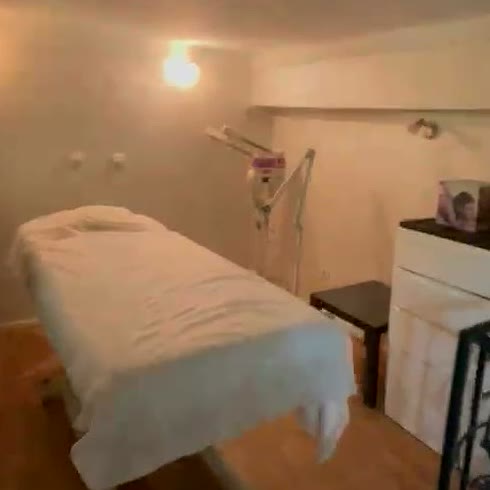 Salle de massage avec une table recouverte d’un drap blanc